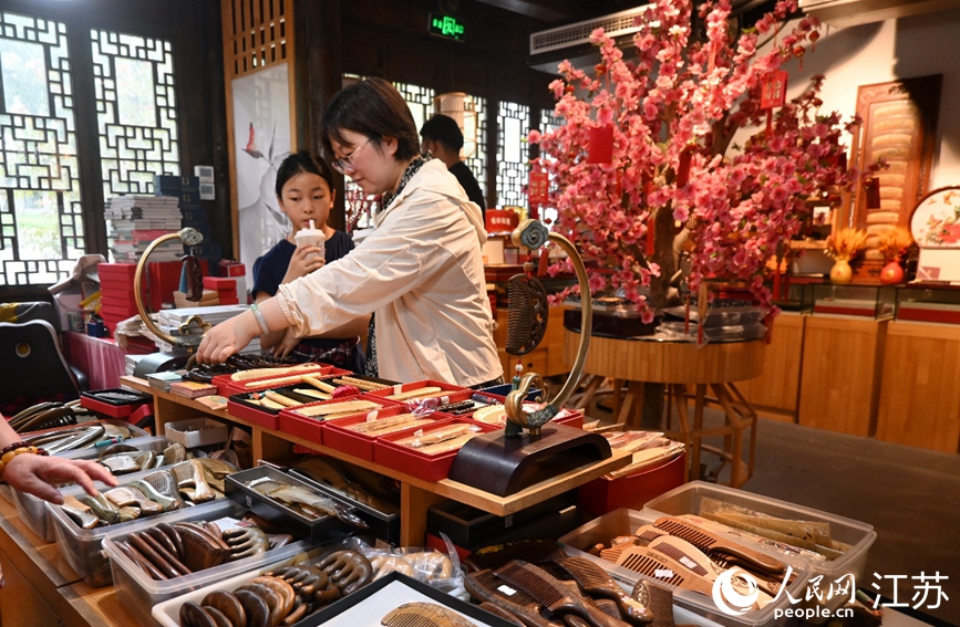 來(lái)自南京的旅客正和女兒一起挑選國(guó)家級(jí)非物質(zhì)文化遺產(chǎn)常州梳篦。人民網(wǎng) 謝地?cái)z